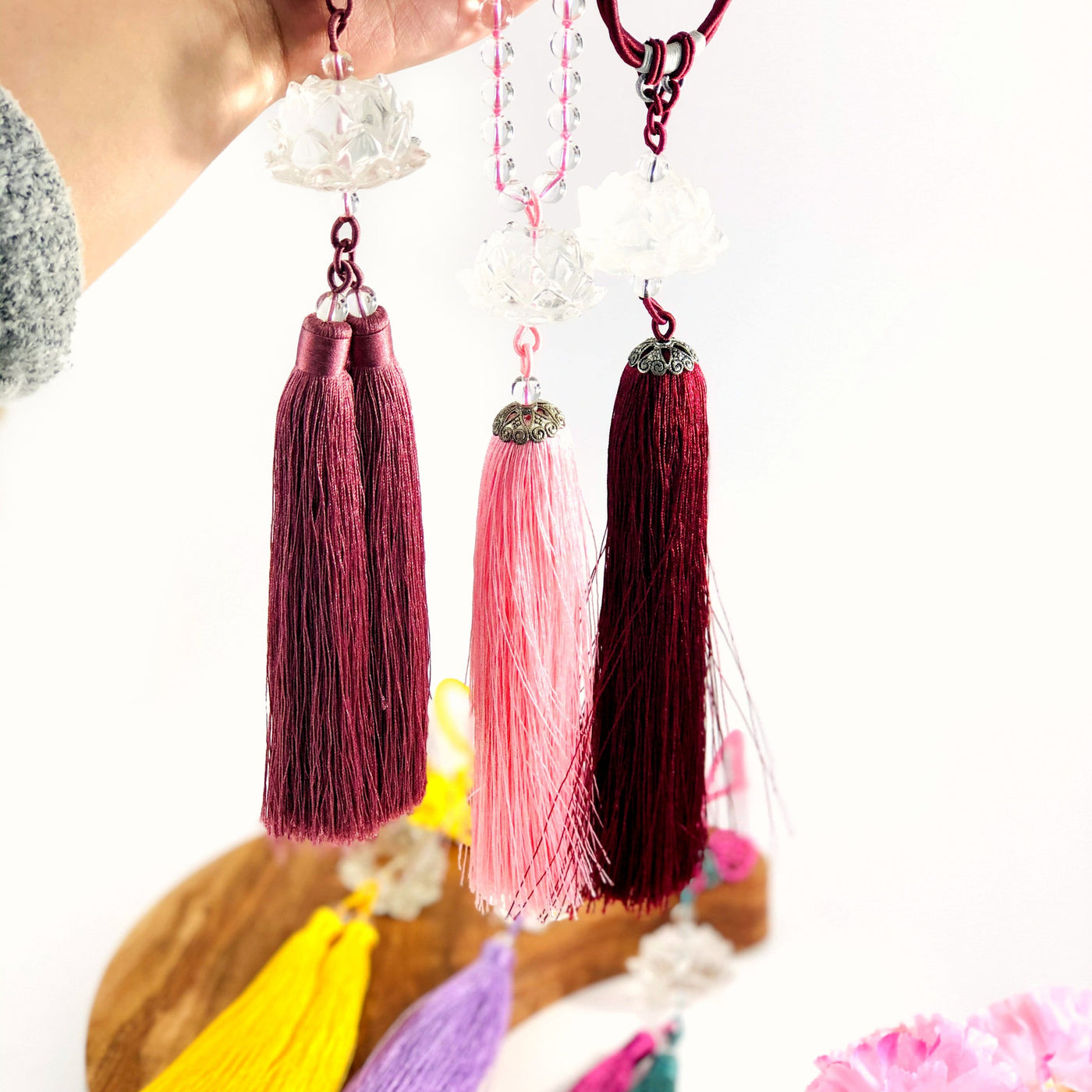 hand holding up 3 different colored Lotus Flower Colored Tassels