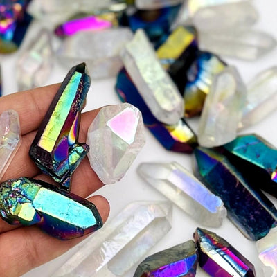 crystal quartz points coated in rainbow titanium or anger aura in hand for size reference 