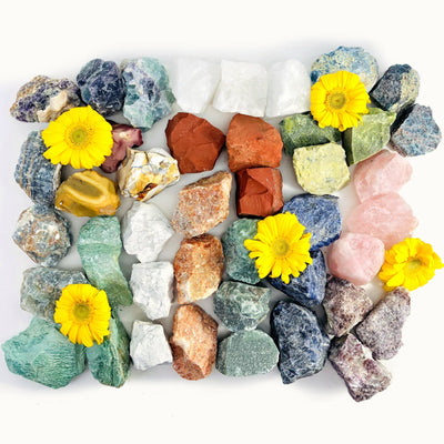 Different types of rough stones scattered on white background with yellow flowers