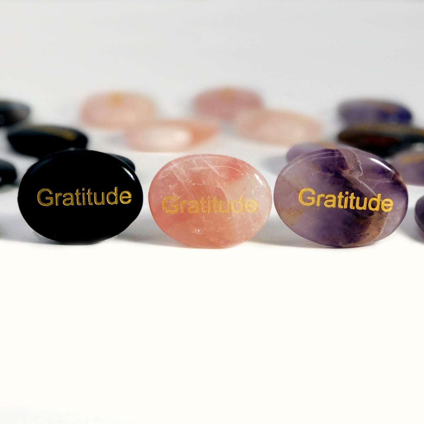 Pocket Stone "Gratitude" Palm Stones, one of each stone propped up on a white surface.