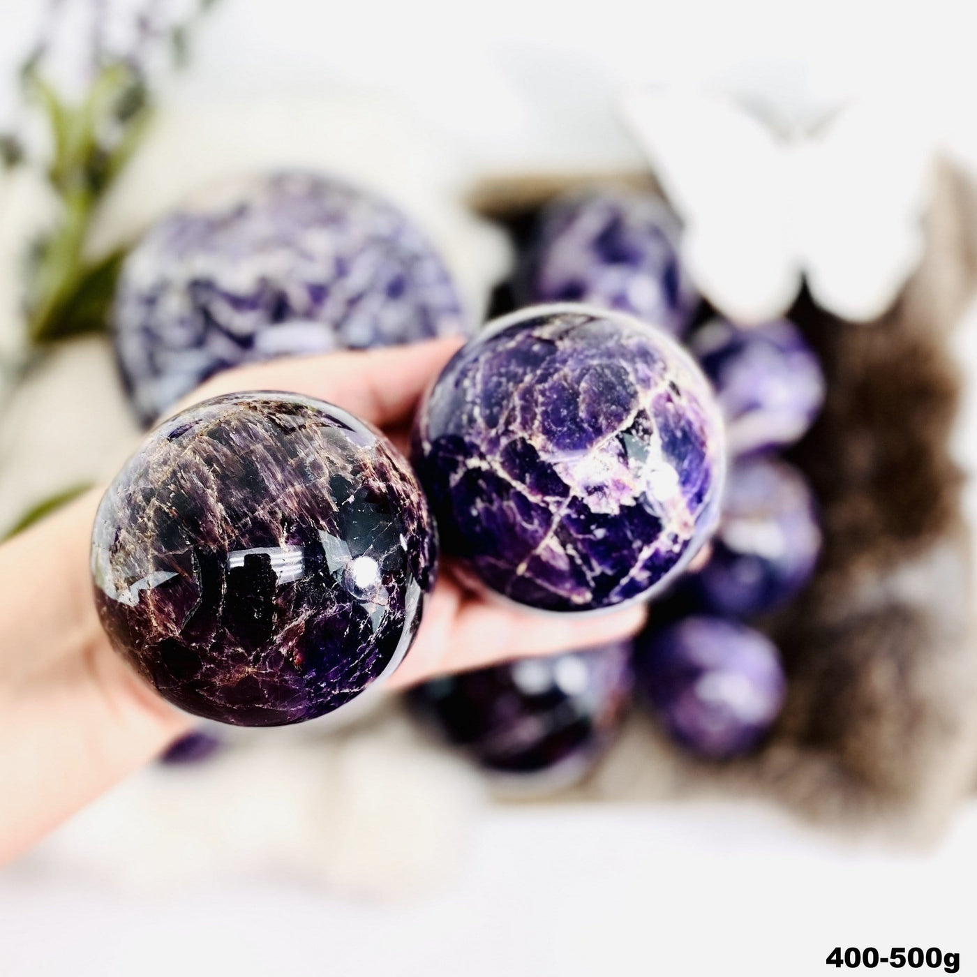 Chevron Amethyst Polished Spheres in a hand, size under 400-500g