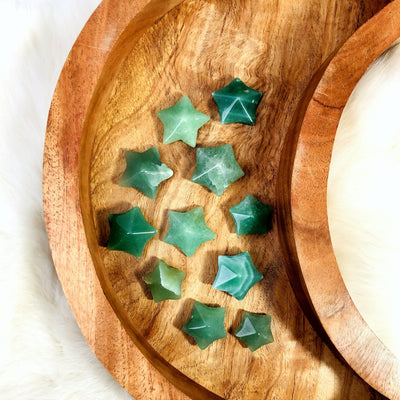 11 Green Aventurine Puffy Star Cabochon Gemstones displayed on a wooden moon shaped tray.