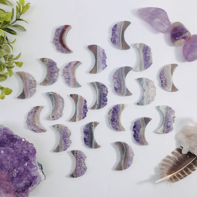 drilled and undrilled Amethyst Moon Crescents laid out on a table to show variations in stone