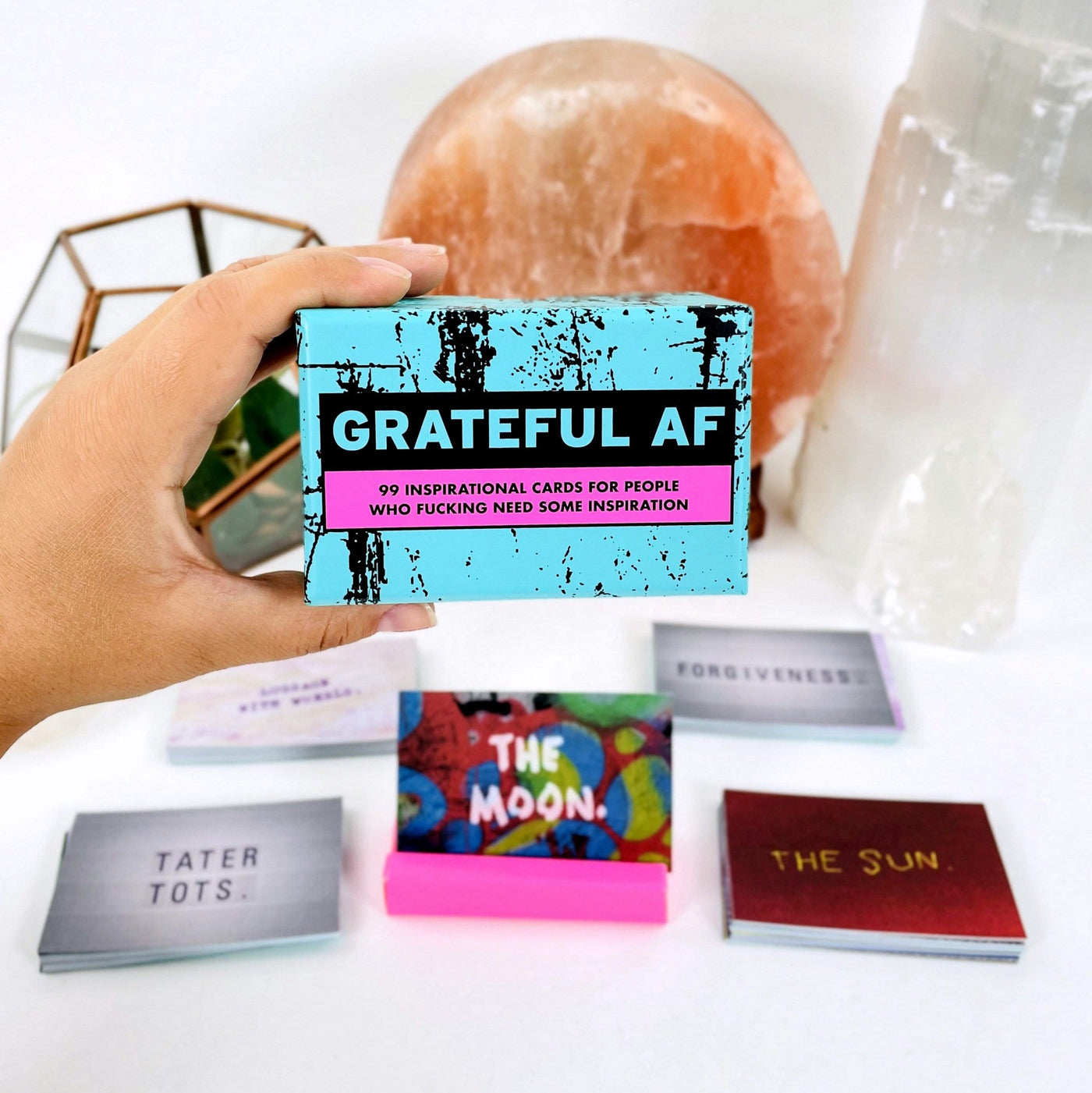hand holding up box for Grateful AF - Inspirational Cards with decorations in the background
