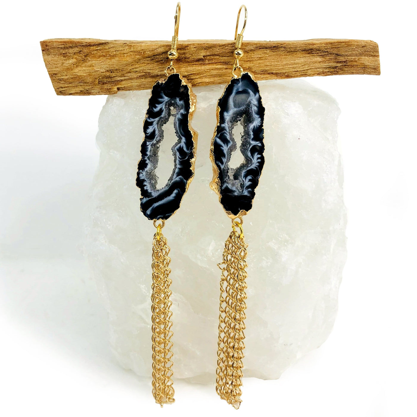 One pair of gold tone agate Geode Slice Dangle Earrings displayed on a crystal with a white background.