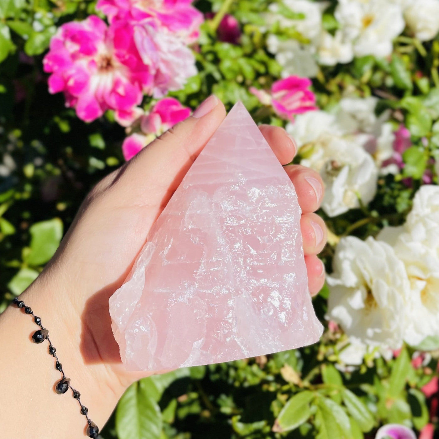 rose quartz point in hand for size reference 