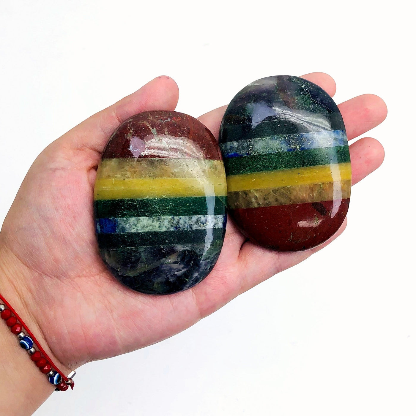 two large seven chakra palm stones in hand for size reference and possible variations