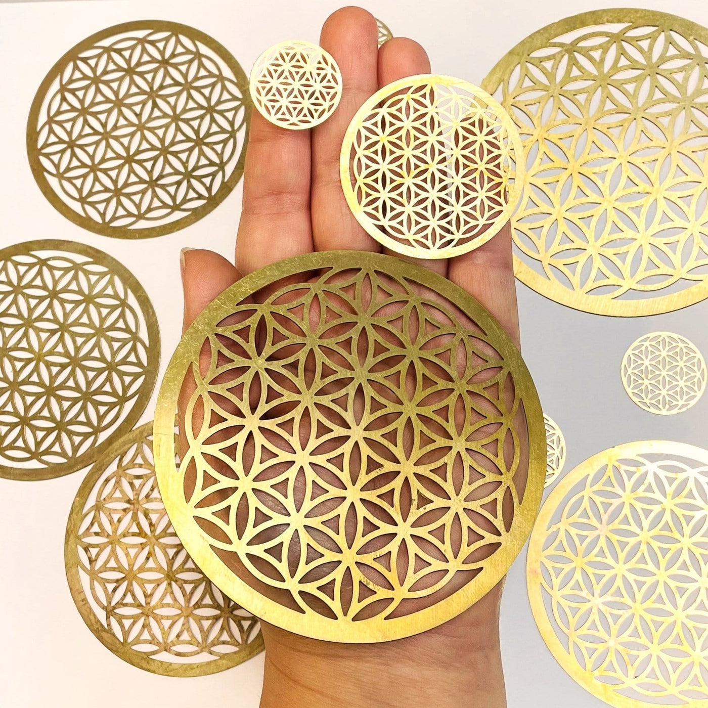 gold toned flower of life grids in hand to show the different sizes 