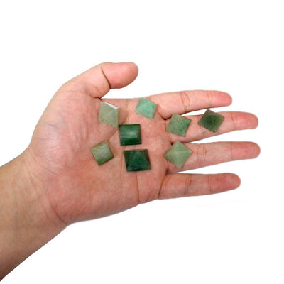 hand holding up 8 green aventurine pyramids for size reference on white background