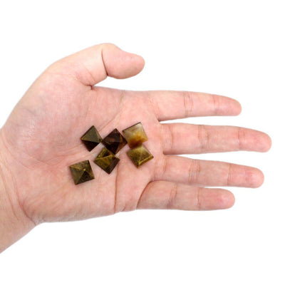 Hand holding 6 pieces of the tiger eye pyramids 