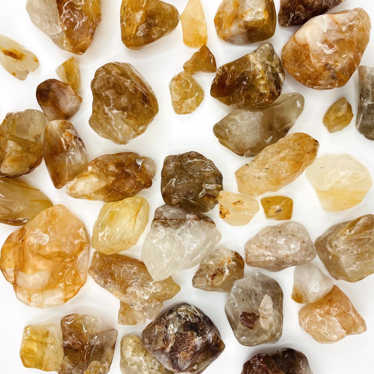 Golden Healer Quartz Polished Tumbled Stones spread out on a table to see varying sizes