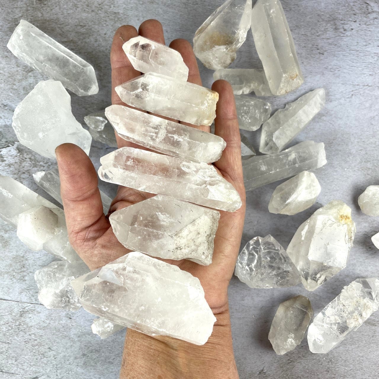 Crystal Quartz Points on a table and in a hand for size reference
