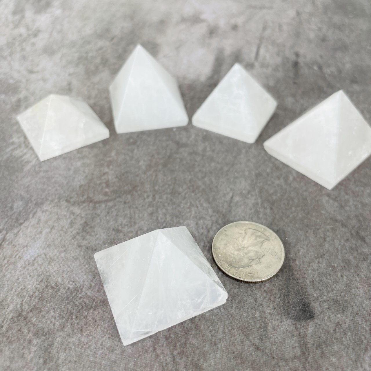 5 Crystal Quartz Pyramids 1.25" size with one  in front next to aaa qurter for size reference