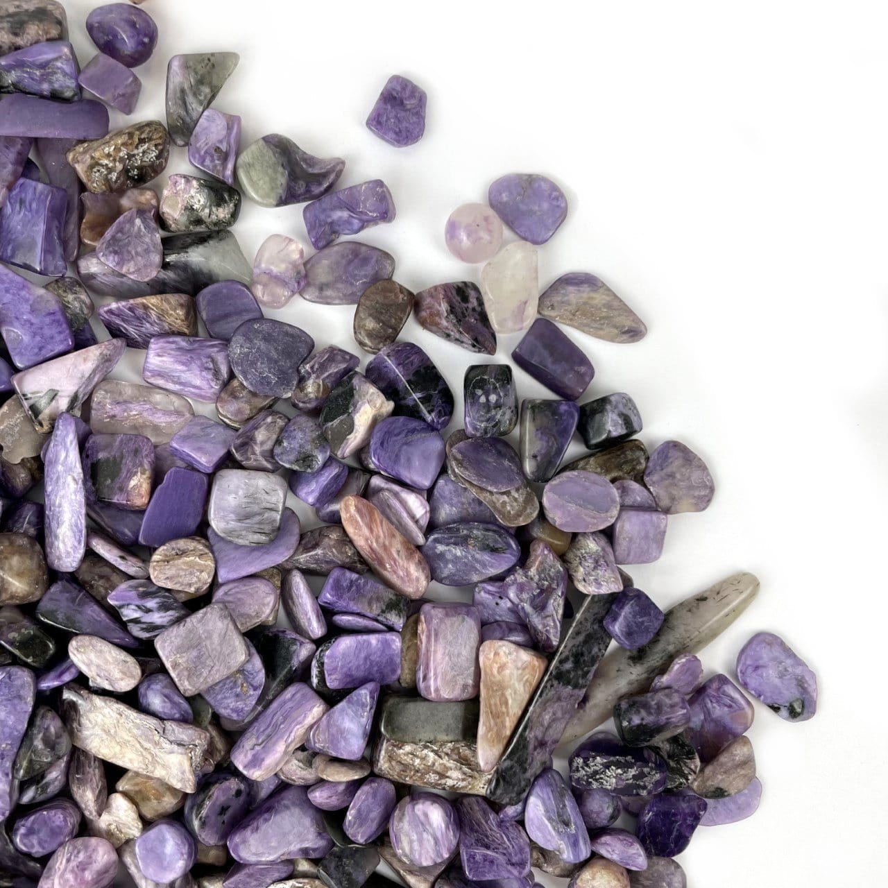 Charoite Chips laid out to show various characteristics such as color size shape texture on white background