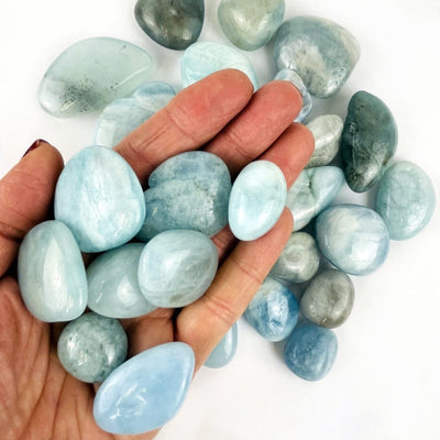 hand holding up Aquamarine Tumbled Stones Nuggets with others in the background