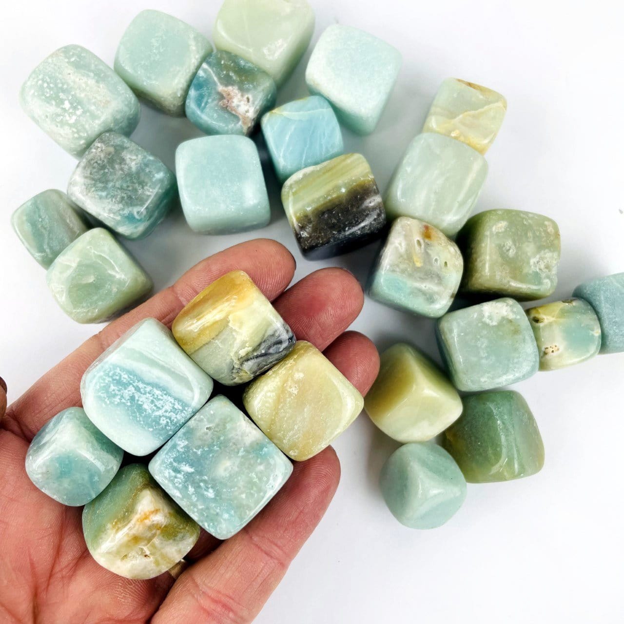 Amazonite cubes being held for size reference, with other cubes in the back ground. 