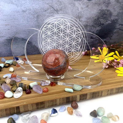 Acrylic Sphere Holder - Crescent Moons with Flower of Life in an alter holding a sphere with flowers and crystals surrounding.