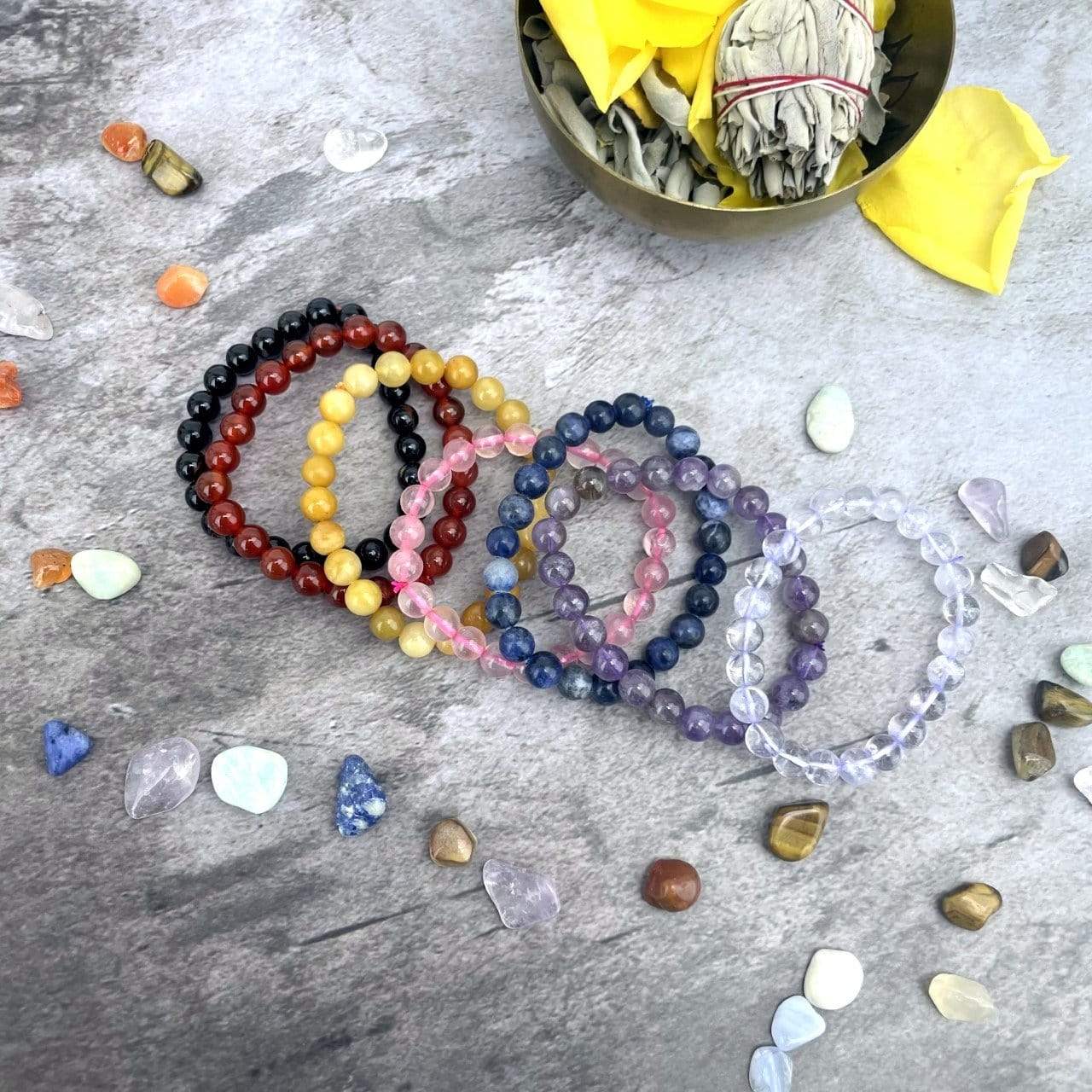 Chakra Bracelet Set - 7 Mala Bead Bracelets laid out on a table