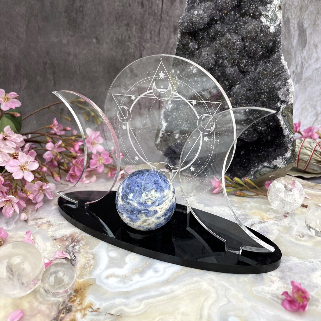 Close up of an Acrylic Sphere Holder Sacred Geometry - 6 Pointed Star holding a sphere in an alter that consists of flowers and crystals.