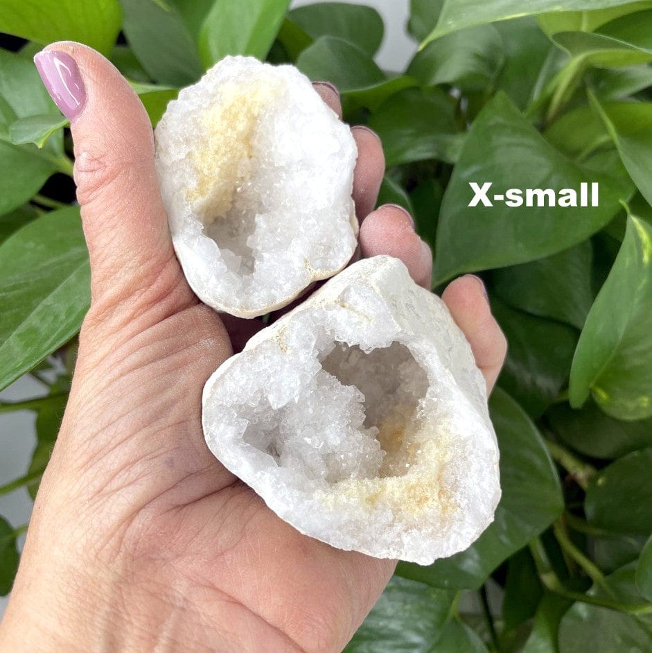 extra small geode halves in a woman's hand to show the white druzy inside