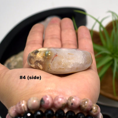 hand holding up Flower Agate Polished Stone Heart showing side view