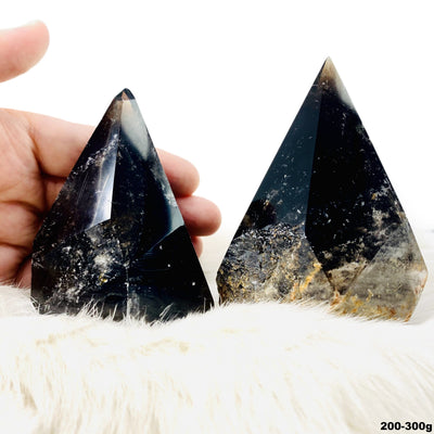 two 200g - 300g smokey quartz semi polished points on display for possible variations with one in hand for size reference