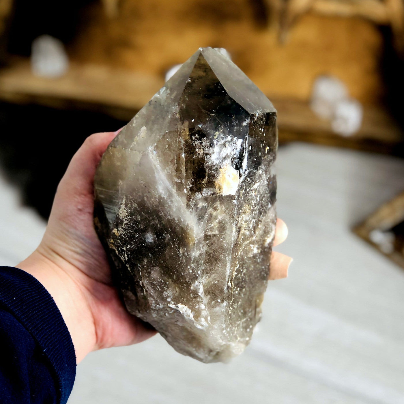 side view of smokey quartz semi-polished point in hand for thickness