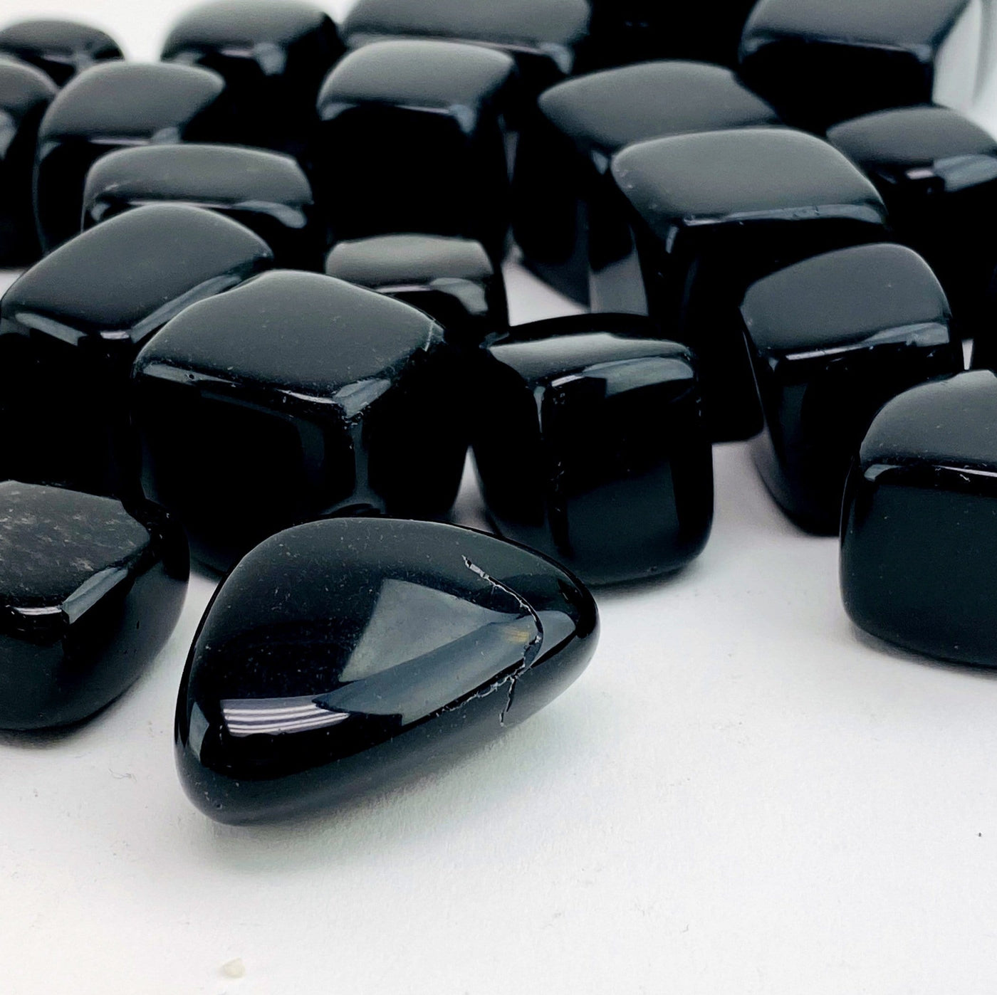 angled shot of tumbled obsidian cubes on white background