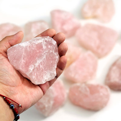 A Hand holding a rose quartz chunk 