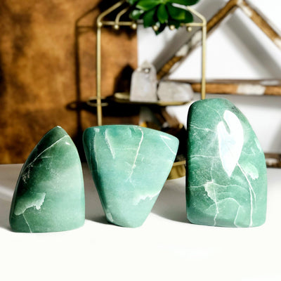 3 aventurine cut bases in front of metal and wooden shelves in the background