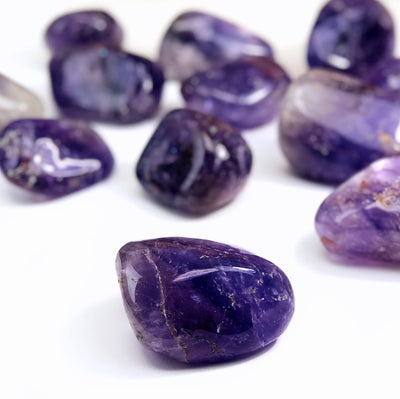 up close shot of amethyst tumbled stone with others blurred on white background
