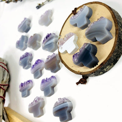 Amethyst slice cut into mushroom shapes with a drill hole on the side.  This photo shows an assortment as they range in colors and patterns with shades of white, gray, brown, purple and tan.