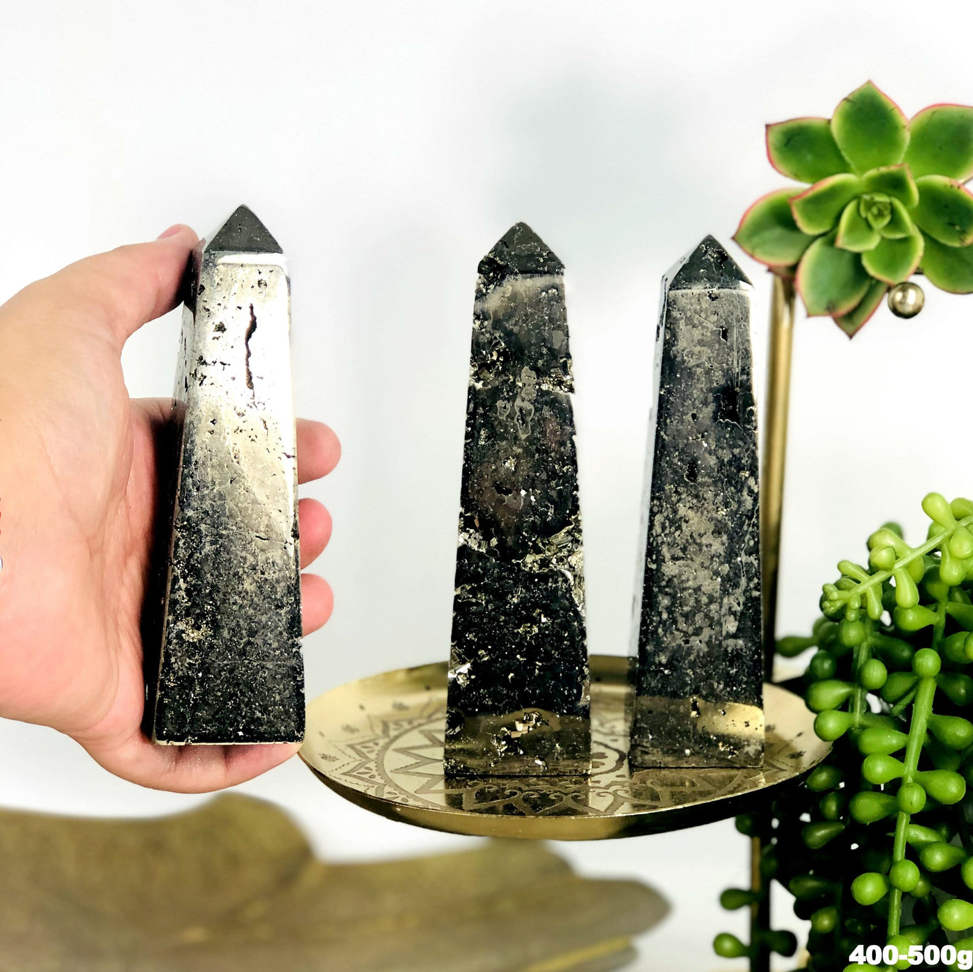3 assorted pyrite towers in the 400 through 500 gram range and one is in a woman's hand.