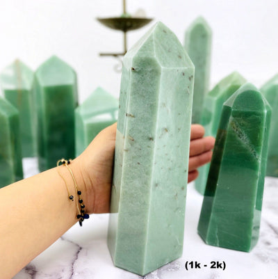 1-2k green quartz tower next to smaller towers and a woman's hand.