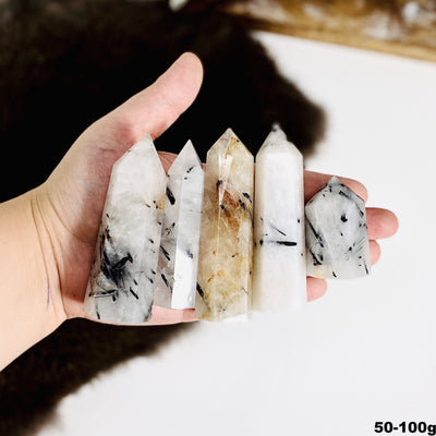 Assorted quartz with black rutilation in a hand.
