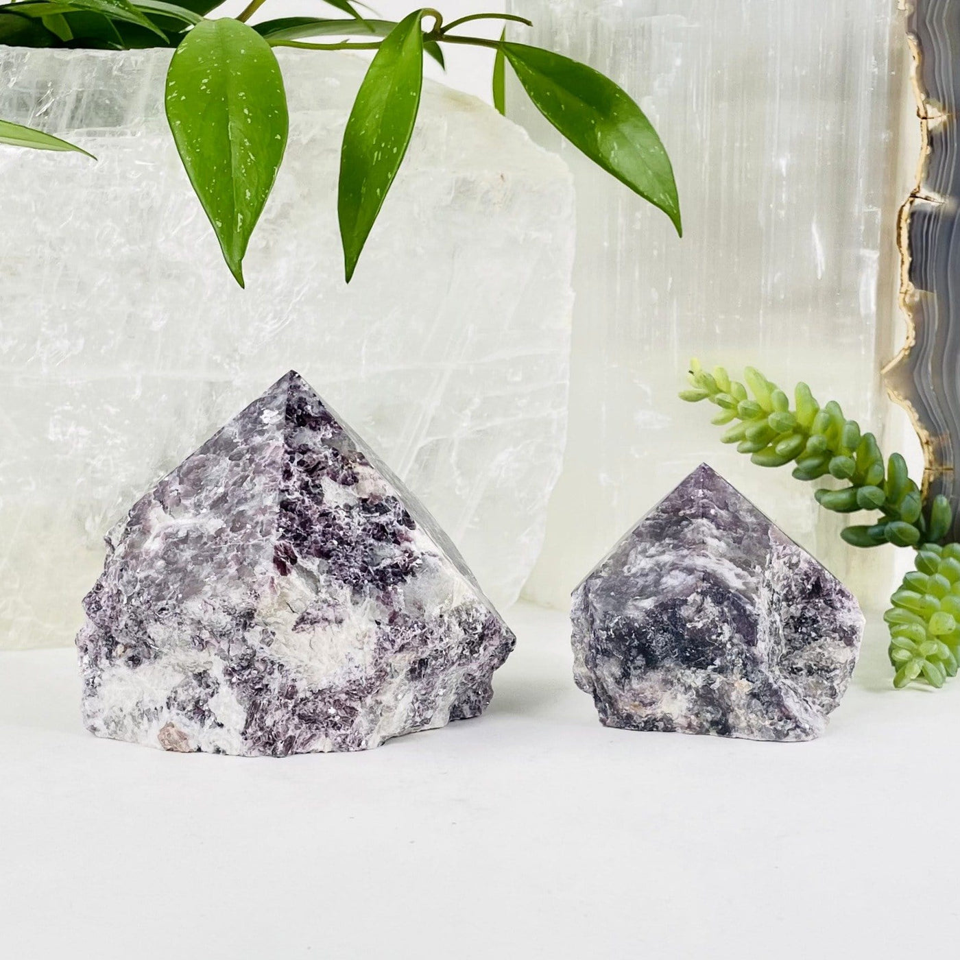 lepidolite semi polished point with decorations in the background
