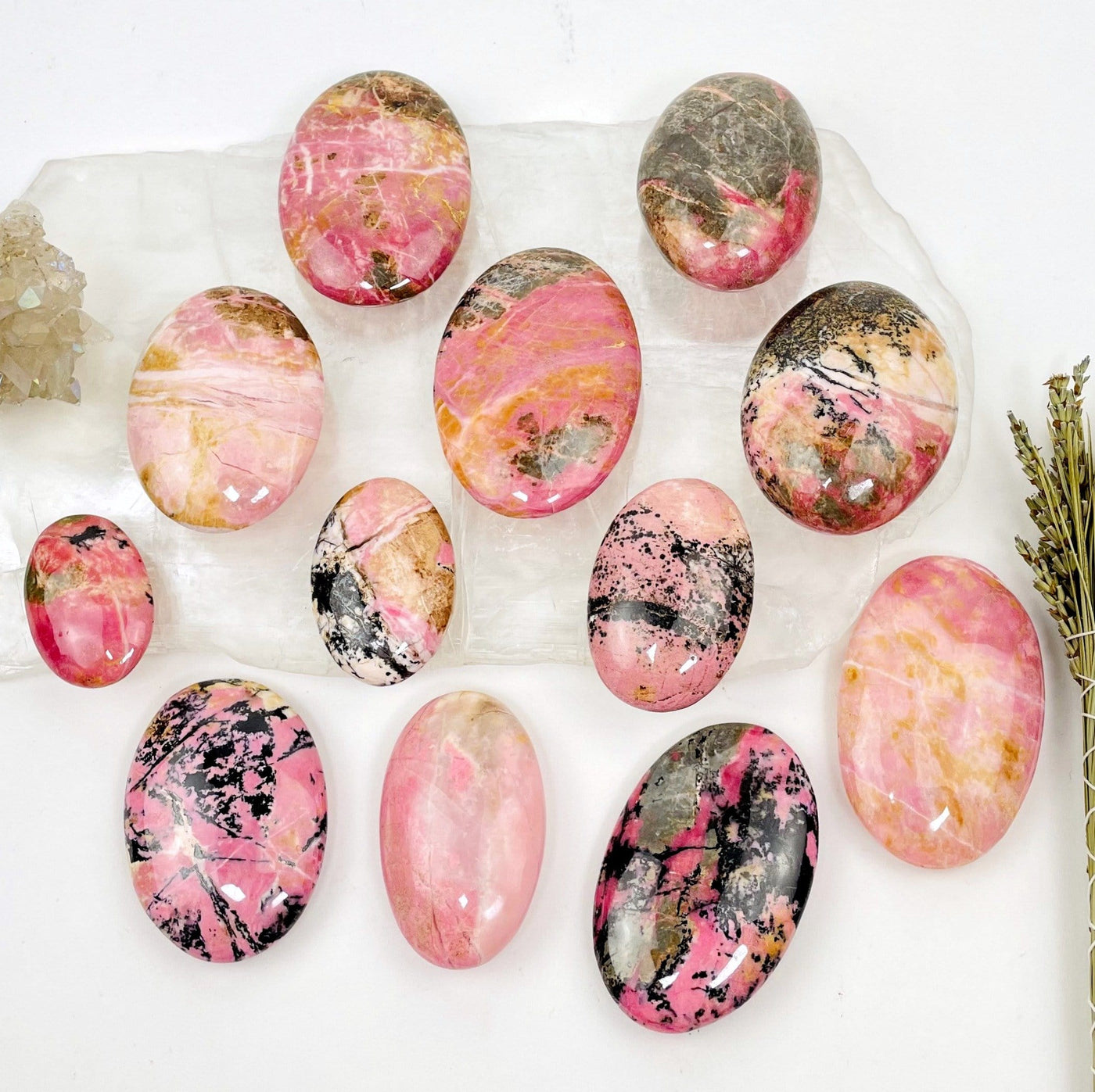 Rhodonite Palm Stones displayed on a selenite slab with decorations