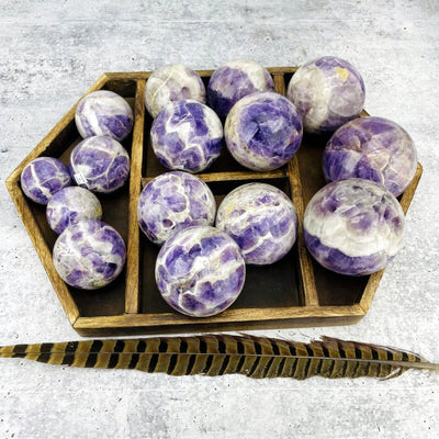 Chevron Amethyst Polished Spheres of all sizes displayed in a wooden case.