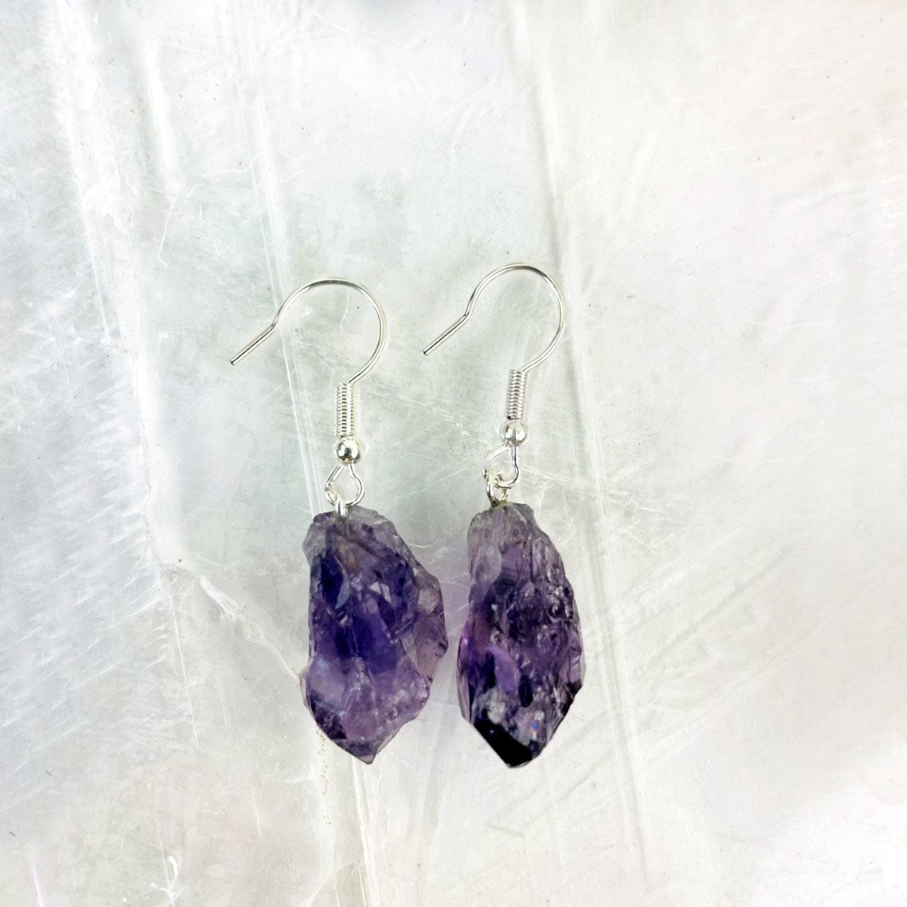 Close up of amethyst point earrings silver plated on a selenite slab.