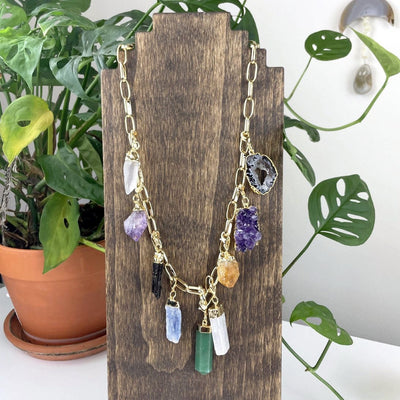 Gold gemstone and charm necklace on a stand