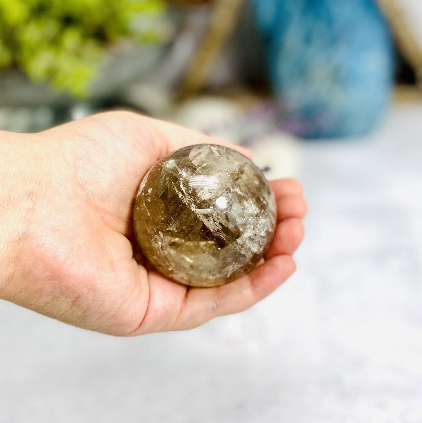 smokey quartz polished sphere in hand for size reference