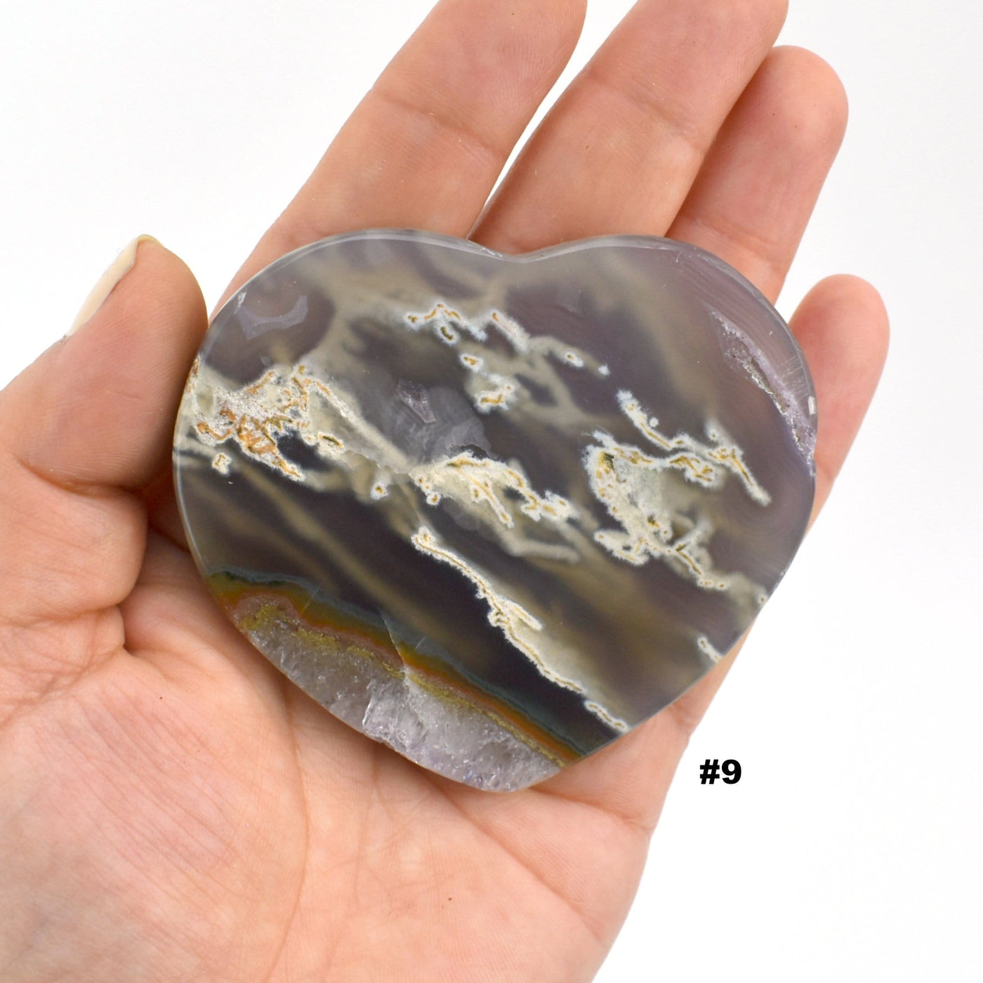 Agate heart slice #9 in a hand with a white background.