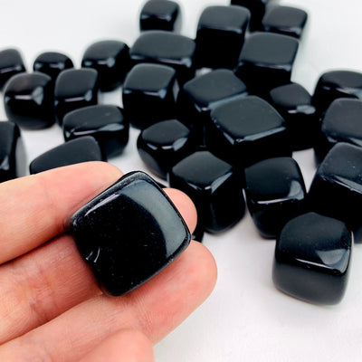 hand holding up one obsidian cube with others in the background