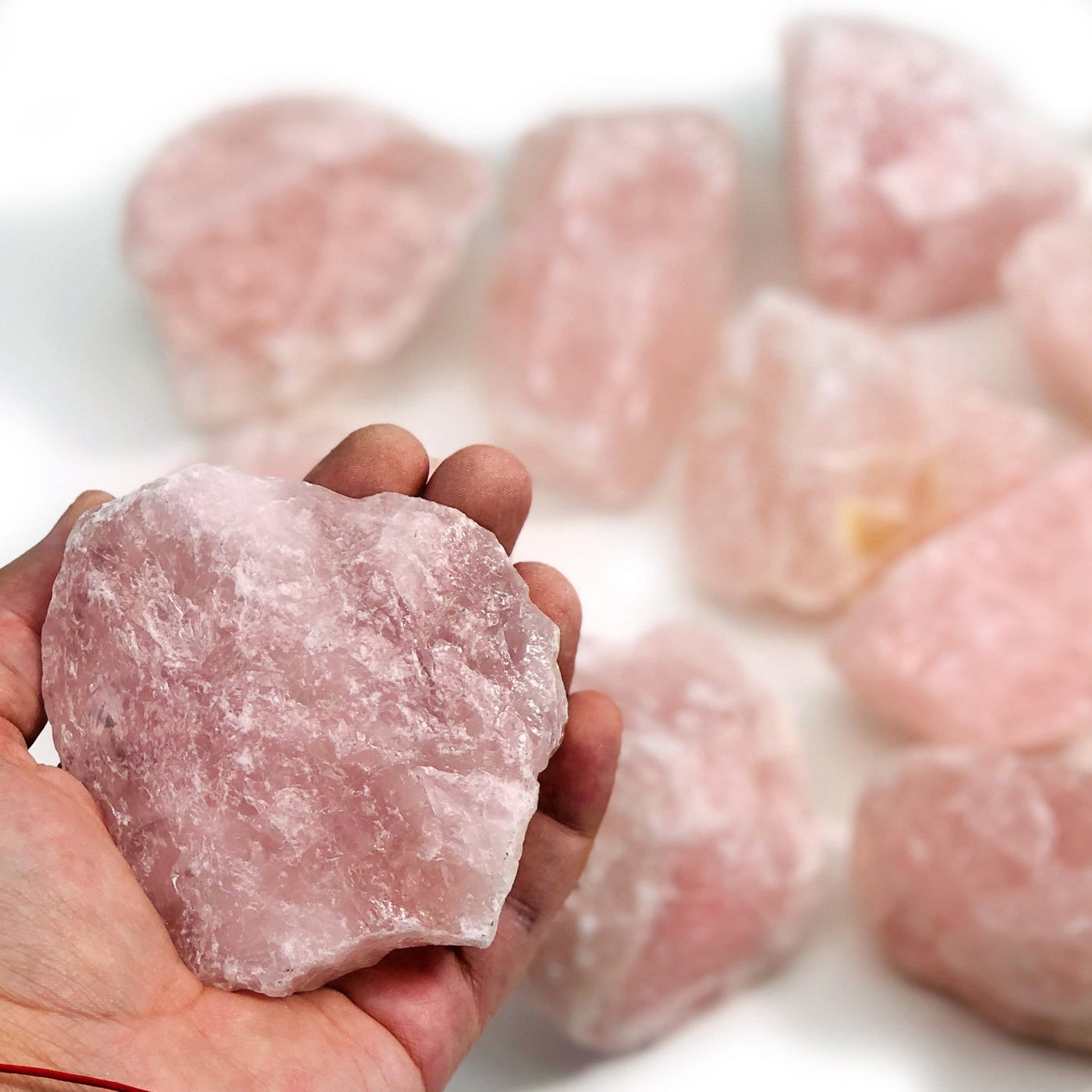 hand holding up rose quartz stone with others in the background