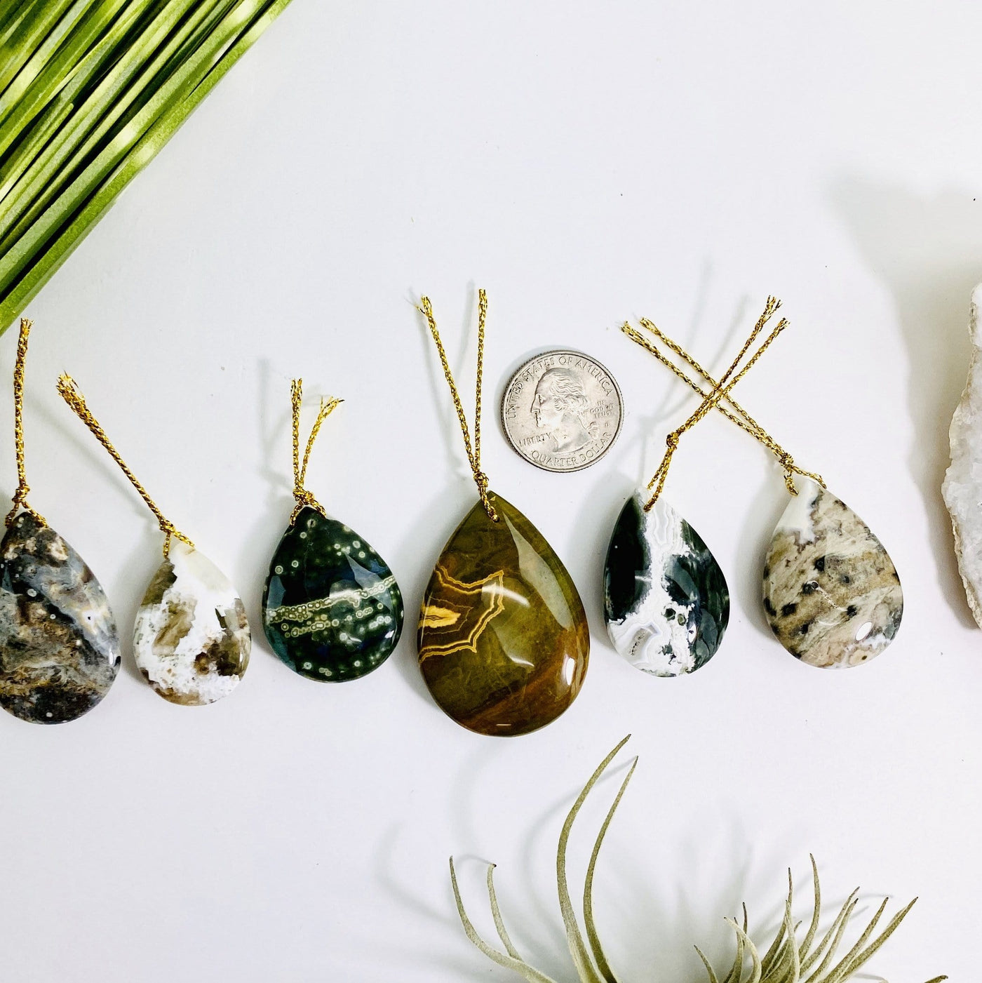 jasper pendants on a table next to a quarter