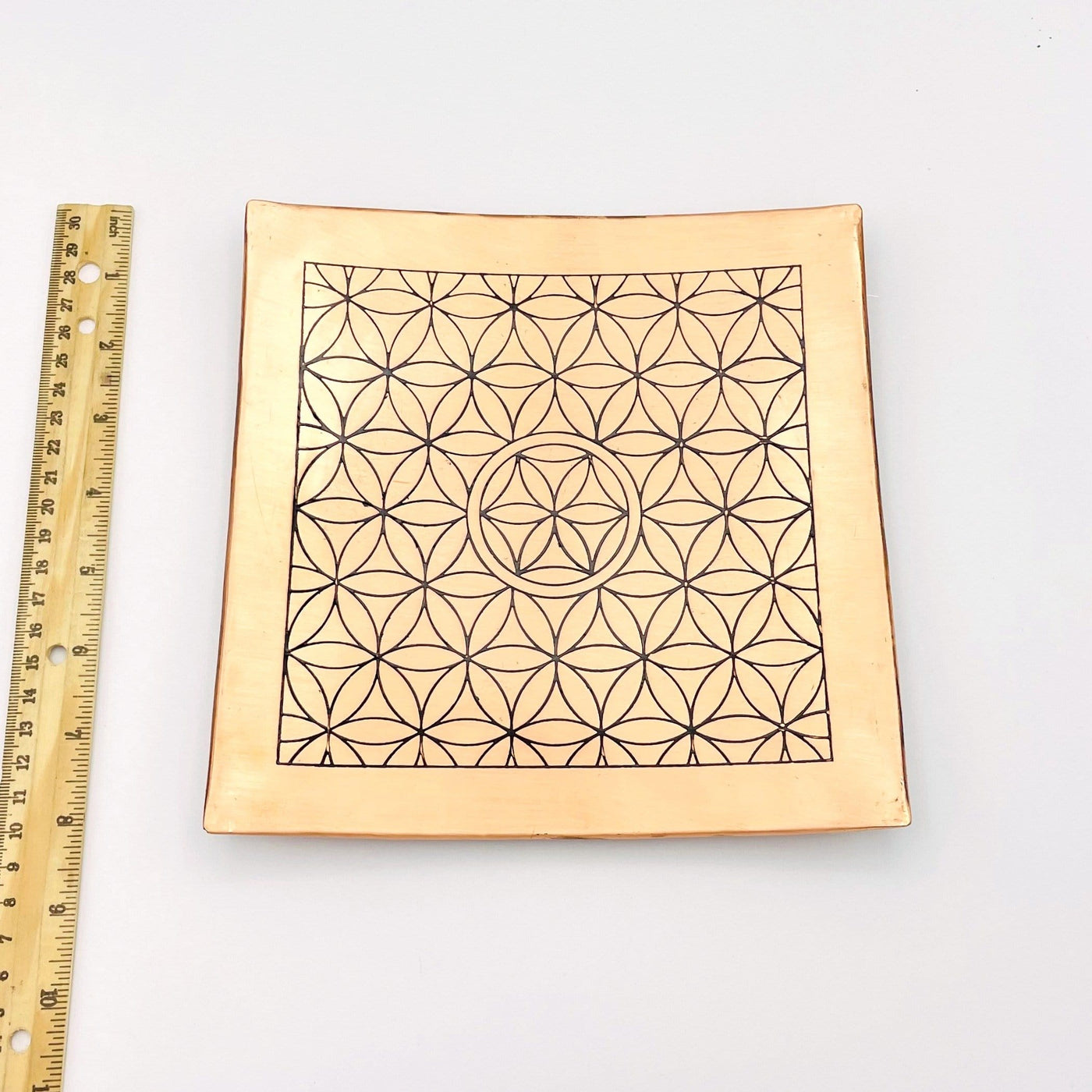 Copper Charging Dish engraved with flower of life  grid next to ruler for size comparison