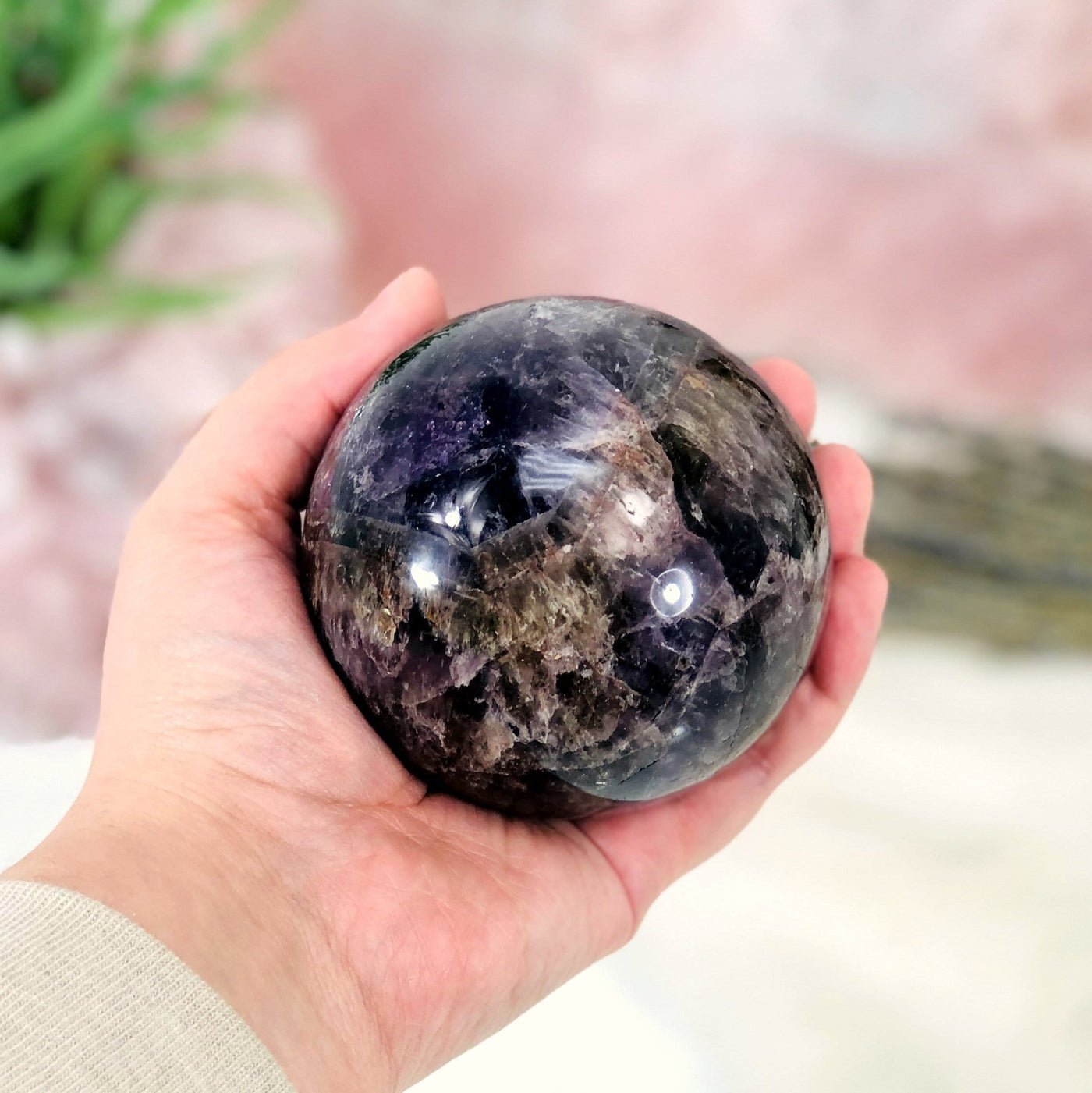 seven minerals polished sphere in hand for size reference