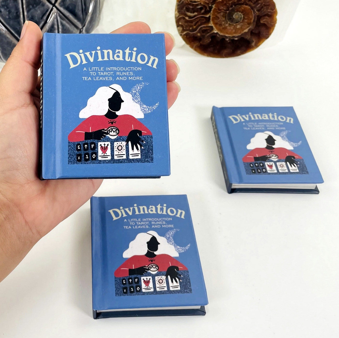 Divination Mini Guidance Book in Hand and 2 more lying Down on White Background.
