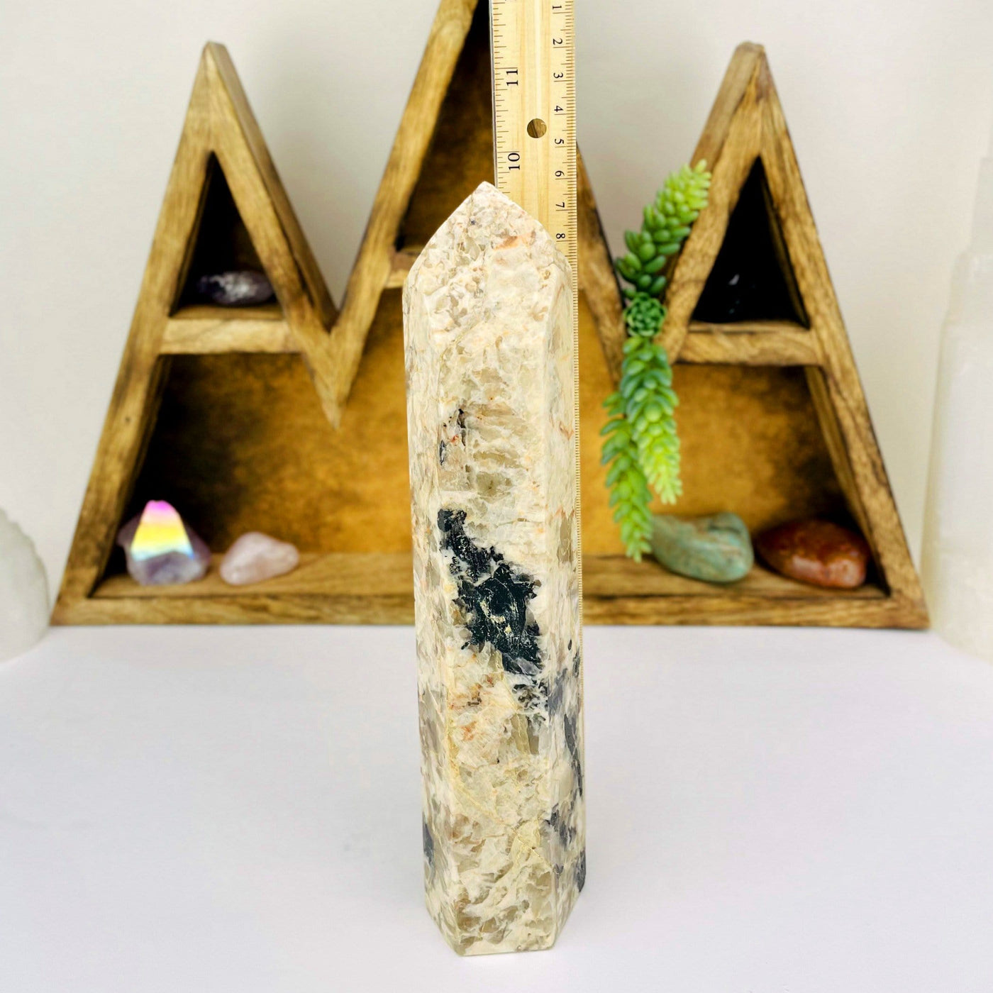 Tourmaline with Feldspar Tower next to a ruler for size reference with decorations in the background