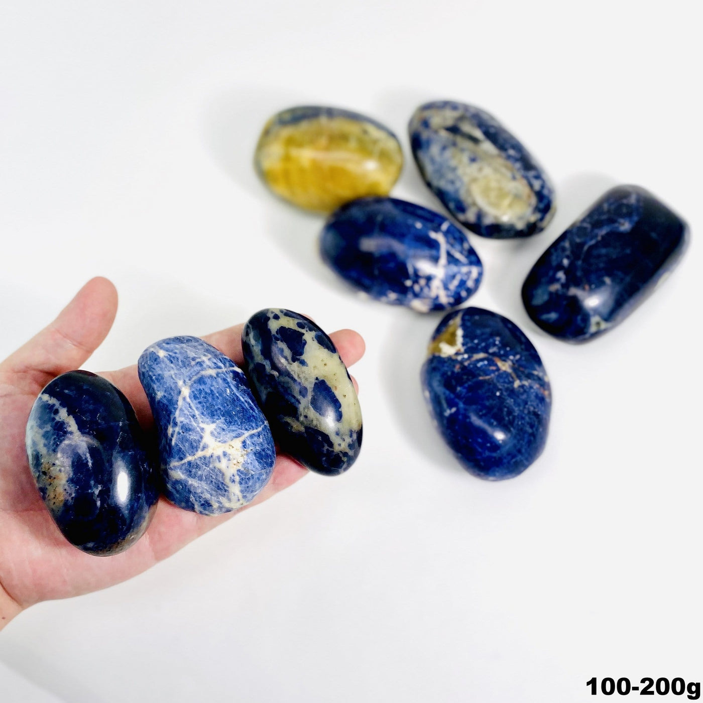 three 100g - 200g sodalite large tumbled stones for size reference with many others in white background for possible variations